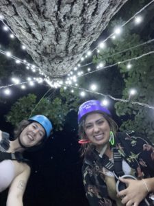 two people looking down at camera with string lights hanging around while at Navitat at Night